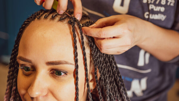 coiffeuse qui réalise une coiffure avec des tresses à une jeune femme